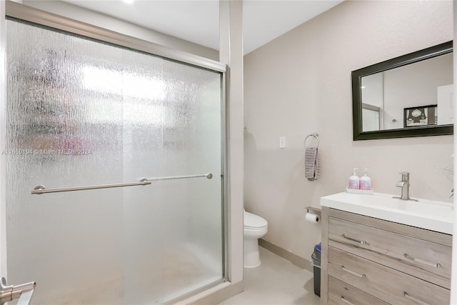 bathroom featuring toilet, a shower with door, and vanity