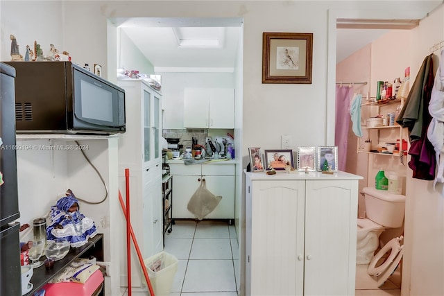 interior space featuring light tile patterned floors and white cabinets