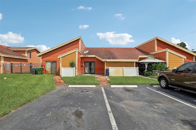 view of front of home featuring uncovered parking, fence, and a front lawn