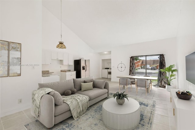 tiled living room featuring high vaulted ceiling and washing machine and dryer