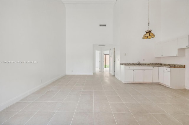 kitchen featuring visible vents, white cabinetry, hanging light fixtures, and a high ceiling