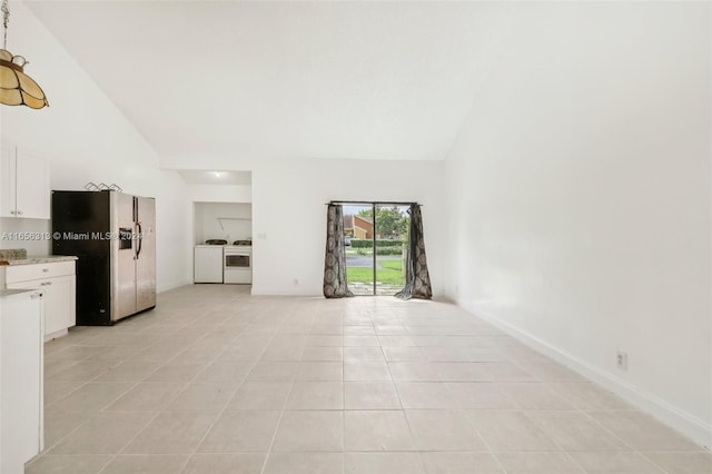 unfurnished living room featuring high vaulted ceiling, light tile patterned floors, baseboards, and washing machine and clothes dryer