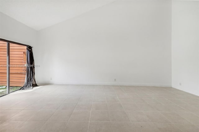 tiled spare room featuring lofted ceiling