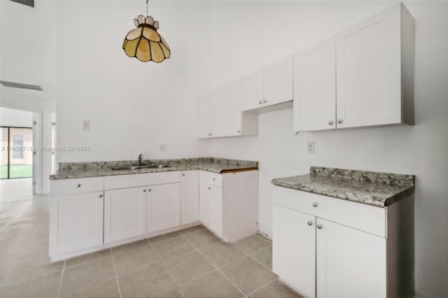 kitchen with pendant lighting, light tile patterned floors, visible vents, white cabinets, and a sink