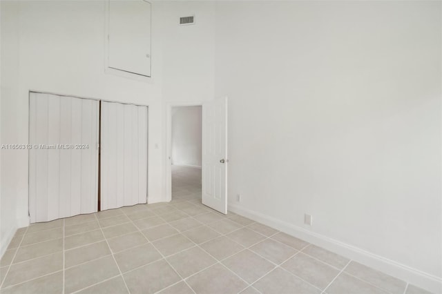 unfurnished bedroom with a high ceiling, light tile patterned flooring, and a closet