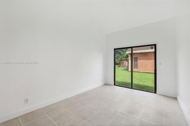 unfurnished room with light tile patterned floors, baseboards, and vaulted ceiling