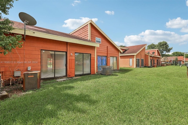 rear view of house with cooling unit and a lawn