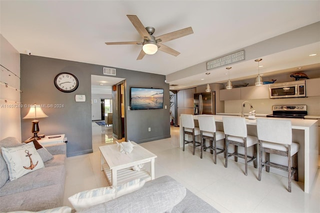 tiled living room featuring ceiling fan and sink