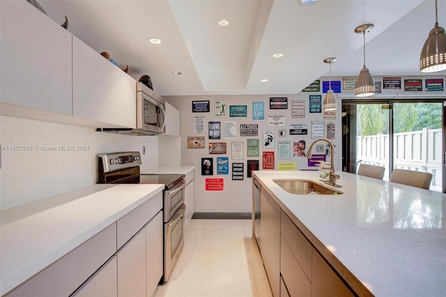 kitchen featuring pendant lighting, stainless steel appliances, sink, and white cabinetry