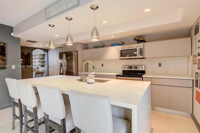 kitchen featuring hanging light fixtures, stainless steel appliances, a center island with sink, and sink