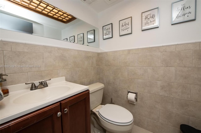 bathroom with vanity, toilet, and tile walls