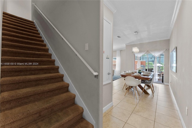 stairs featuring ornamental molding, tile patterned floors, and an inviting chandelier