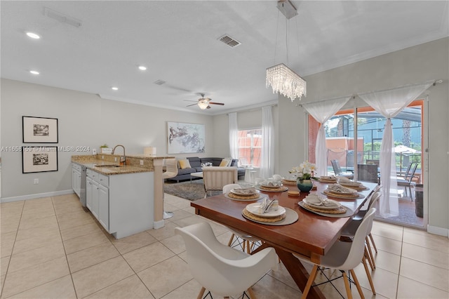 tiled dining area featuring ornamental molding, sink, and ceiling fan with notable chandelier