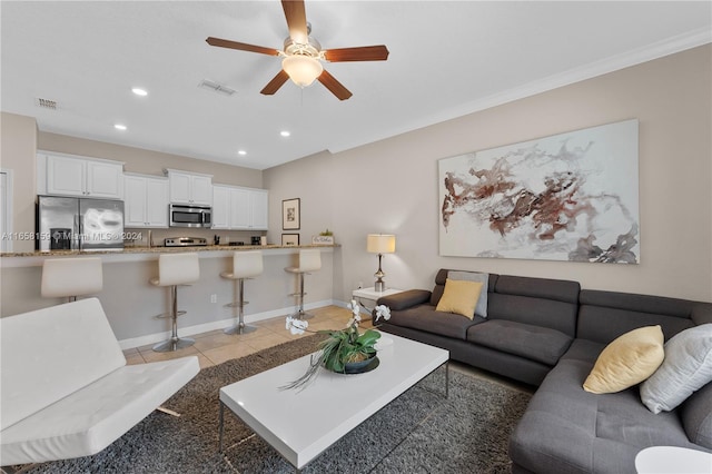 tiled living room with ornamental molding and ceiling fan