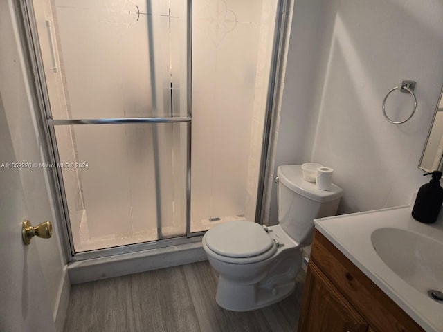 bathroom with vanity, toilet, an enclosed shower, and hardwood / wood-style floors