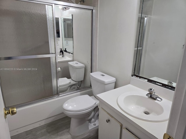 full bathroom featuring vanity, toilet, hardwood / wood-style flooring, and bath / shower combo with glass door