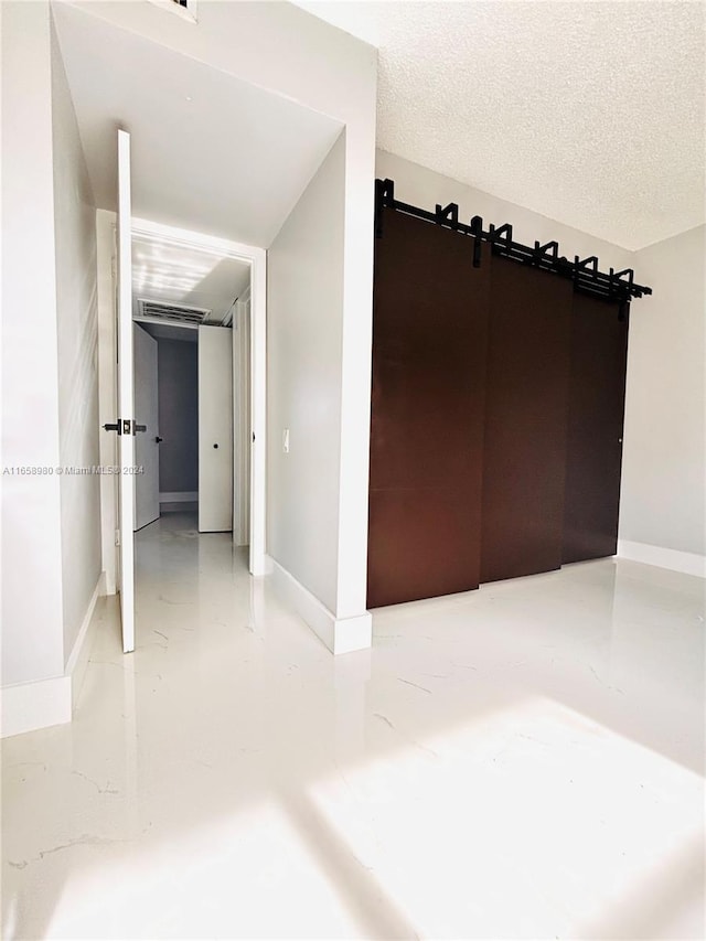 interior space featuring a textured ceiling, a barn door, and concrete flooring