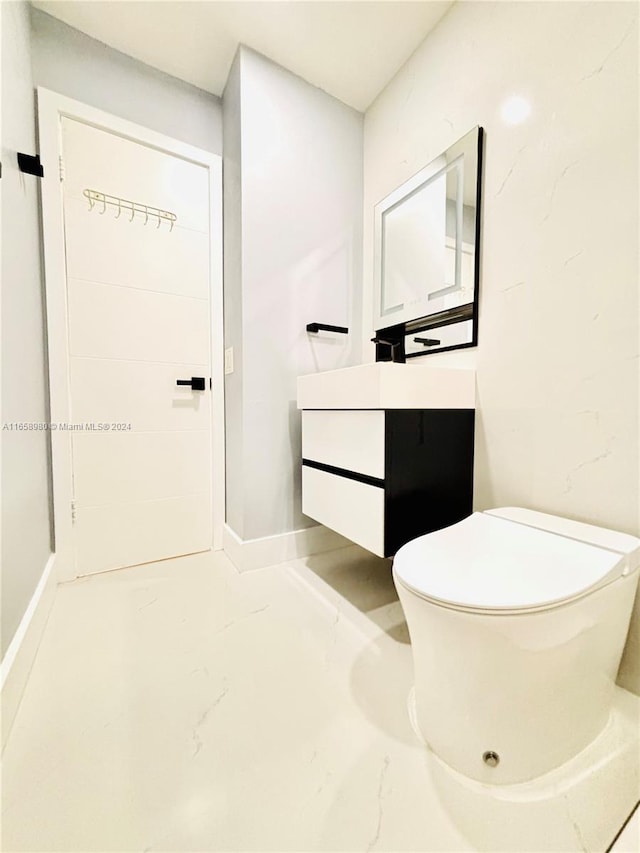 bathroom with concrete floors, vanity, and toilet