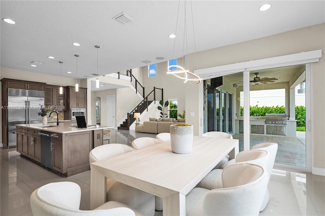 tiled dining space with sink and ceiling fan with notable chandelier