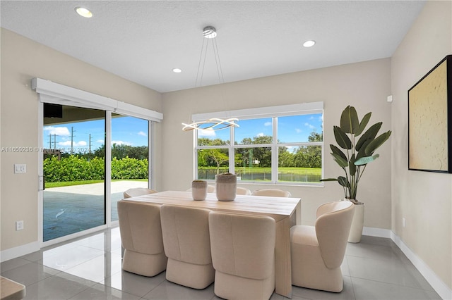 tiled dining space with a textured ceiling and an inviting chandelier