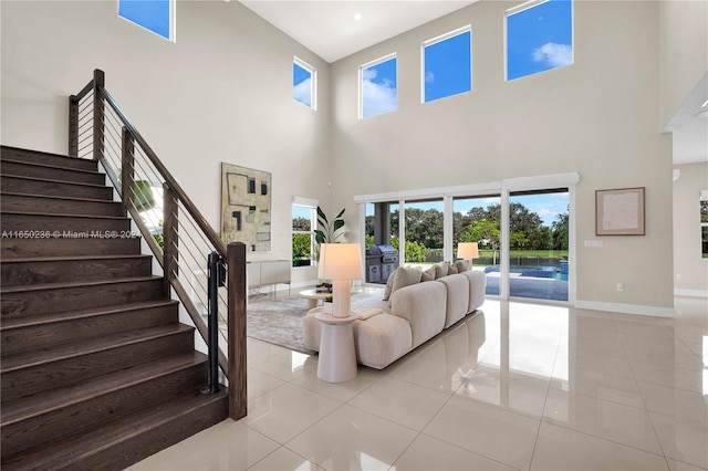 living room with a healthy amount of sunlight, a towering ceiling, light tile patterned flooring, and a wood stove