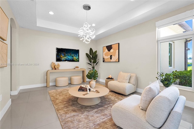 living room with a chandelier, light tile patterned flooring, and a raised ceiling