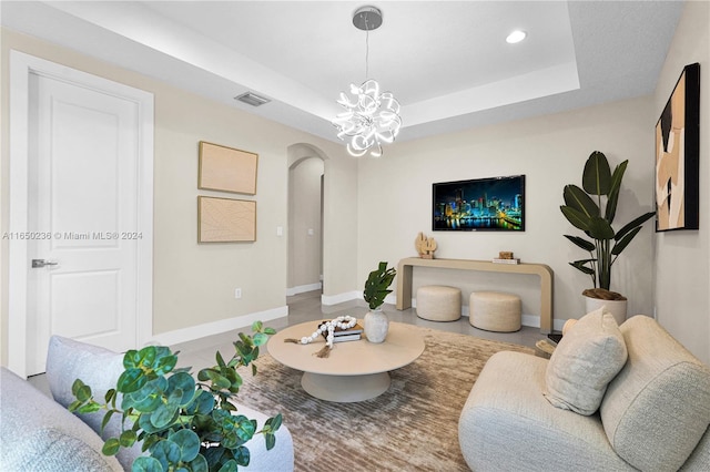 living room with a notable chandelier and a raised ceiling