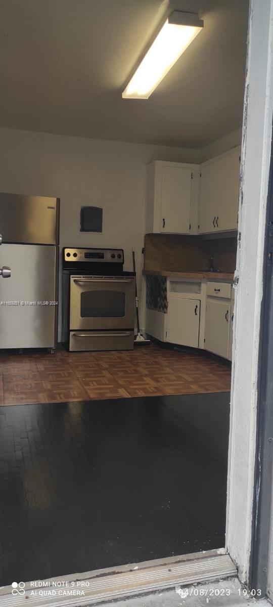 kitchen with dark wood-type flooring, stainless steel appliances, and white cabinetry