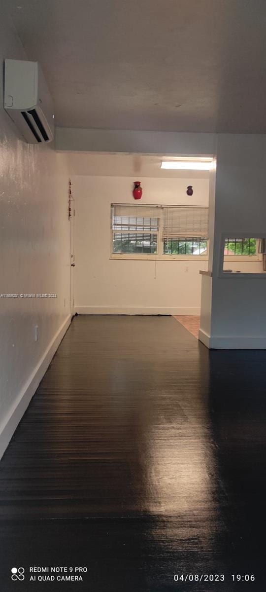 spare room featuring an AC wall unit and dark hardwood / wood-style floors