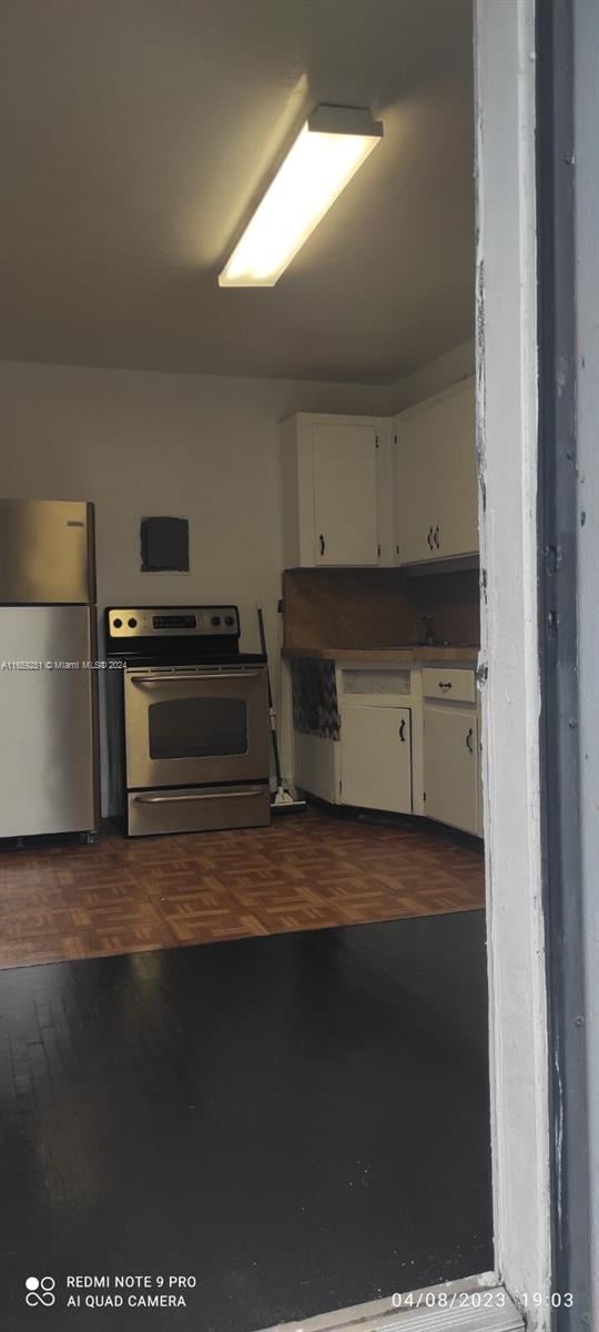 kitchen featuring stainless steel appliances, dark hardwood / wood-style floors, and white cabinetry