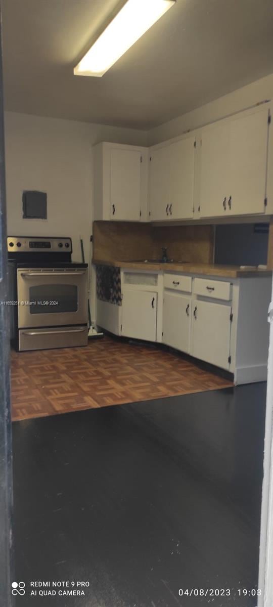 kitchen with stainless steel electric range and white cabinetry