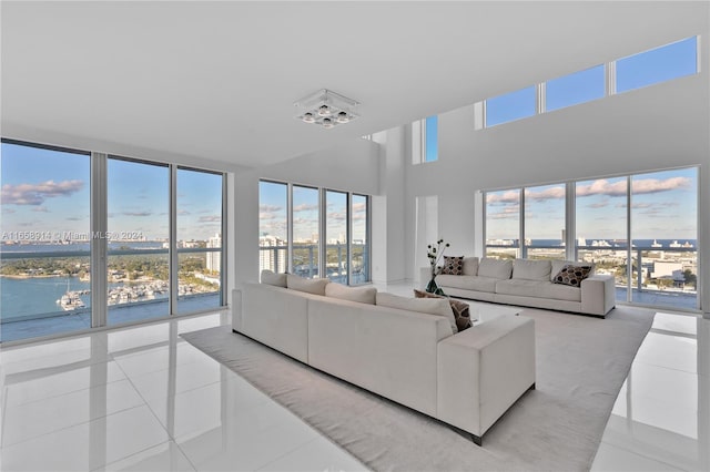 tiled living room with a high ceiling and a water view