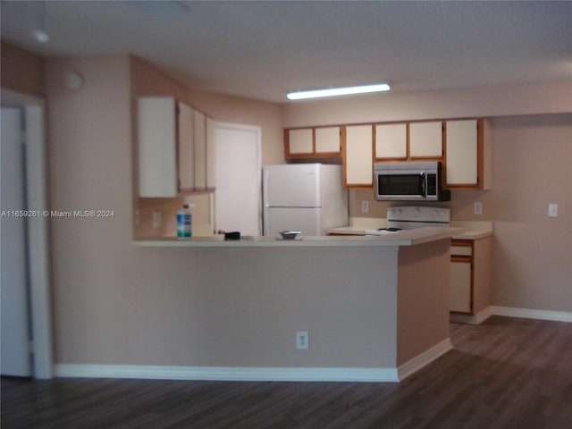 kitchen with dark wood-type flooring, white appliances, and kitchen peninsula