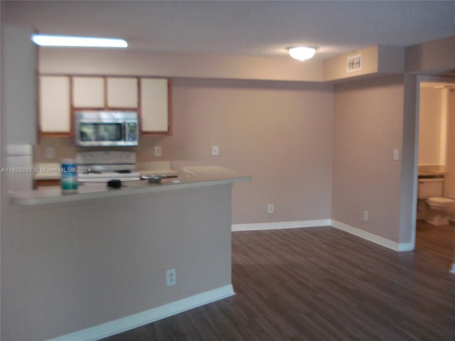 kitchen featuring a textured ceiling, dark hardwood / wood-style flooring, range, kitchen peninsula, and white cabinetry