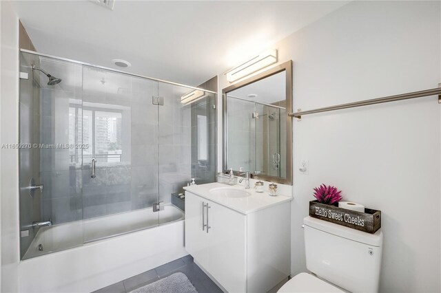 full bathroom featuring tile patterned floors, vanity, toilet, and bath / shower combo with glass door