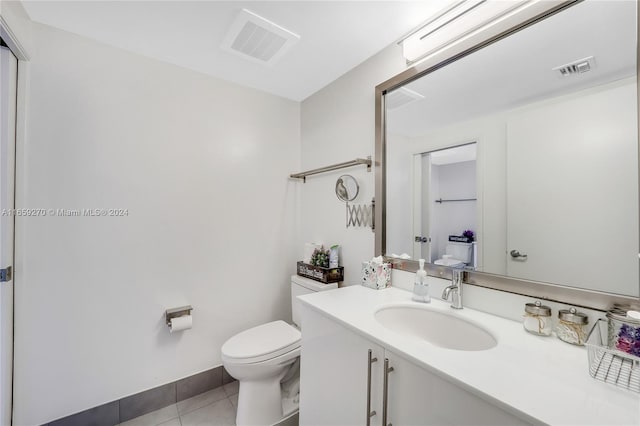 bathroom with toilet, vanity, and tile patterned floors