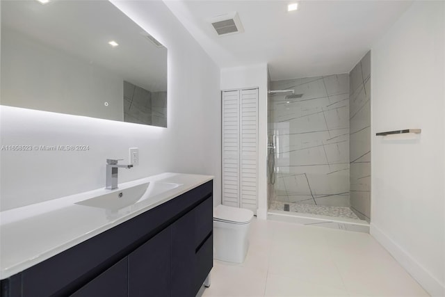 bathroom featuring tile patterned floors, vanity, a tile shower, and toilet