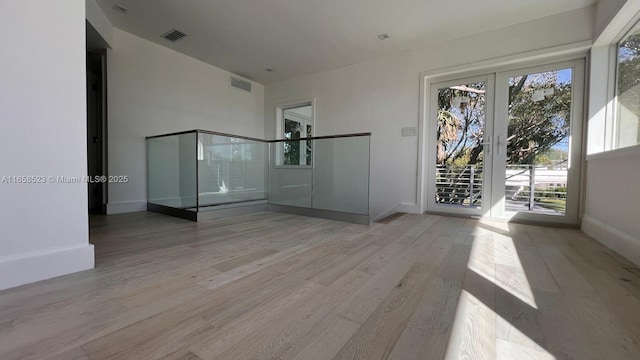 unfurnished room with light wood-type flooring, visible vents, and baseboards