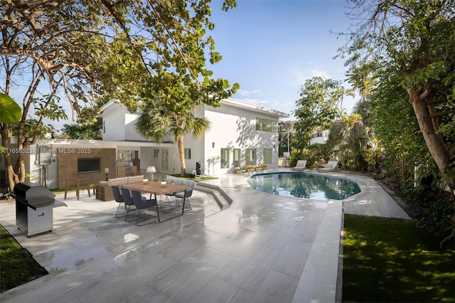 outdoor pool with a patio and area for grilling