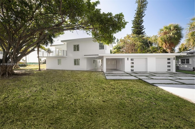 rear view of house featuring a yard, stucco siding, concrete driveway, a balcony, and a garage