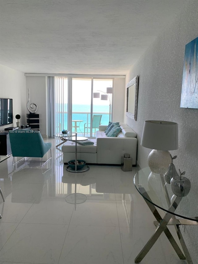 living room featuring a textured ceiling, floor to ceiling windows, and a water view