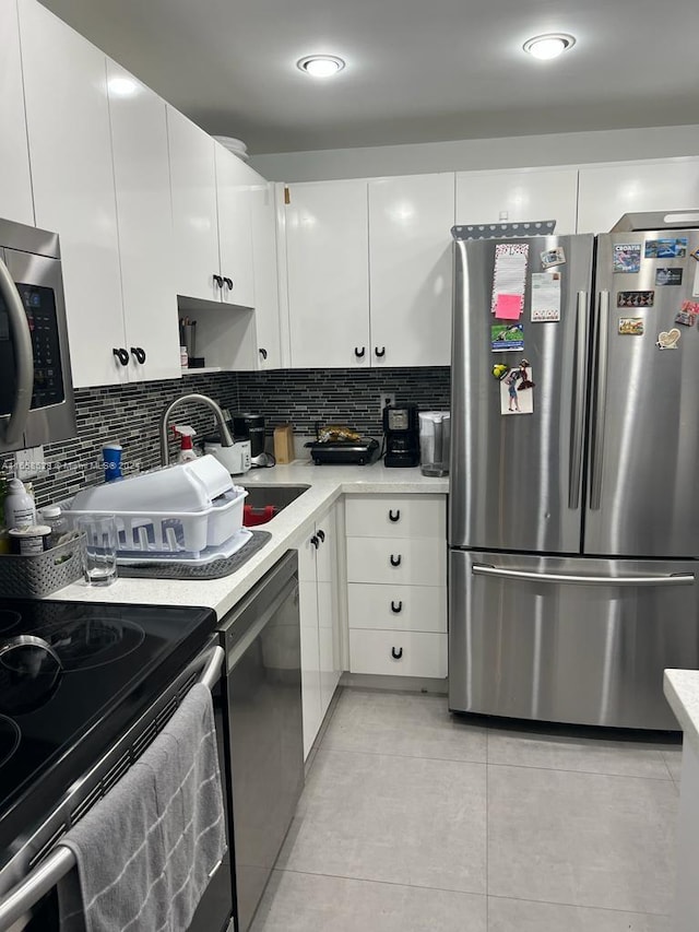 kitchen featuring white cabinetry, backsplash, light tile patterned floors, sink, and appliances with stainless steel finishes