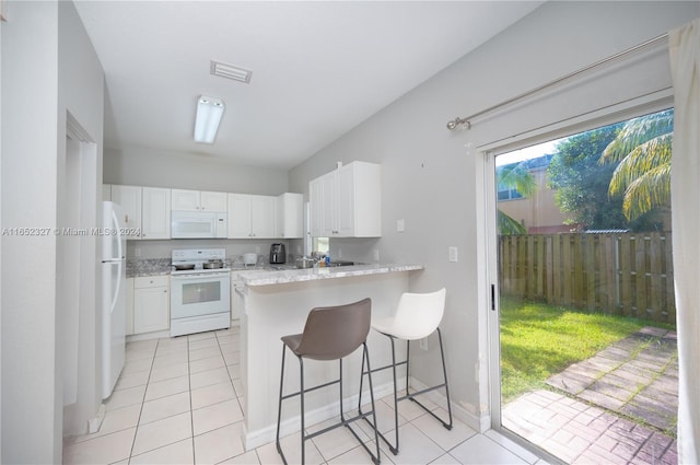 kitchen with white appliances, kitchen peninsula, a kitchen bar, and white cabinets