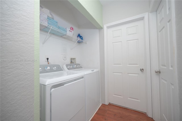 clothes washing area with dark wood-type flooring and separate washer and dryer