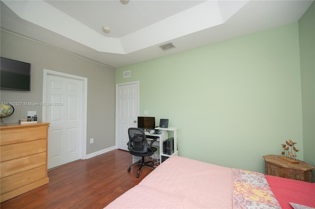 bedroom featuring a tray ceiling and dark hardwood / wood-style floors