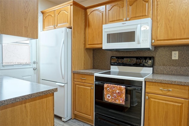 kitchen with tasteful backsplash, white appliances, and light hardwood / wood-style floors