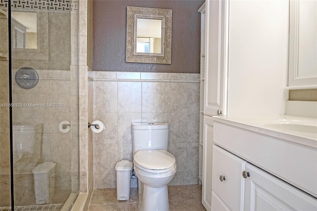 bathroom featuring tile walls, tile patterned flooring, vanity, a tile shower, and toilet