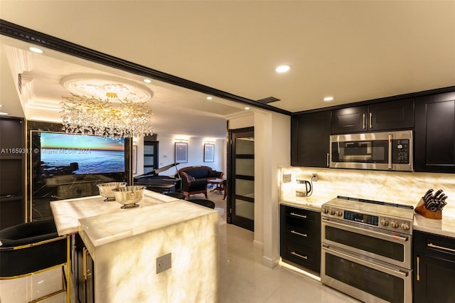 kitchen with crown molding, appliances with stainless steel finishes, a notable chandelier, and decorative backsplash