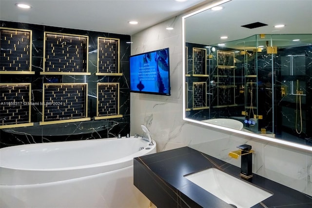 bathroom with a tub, vanity, and tile walls