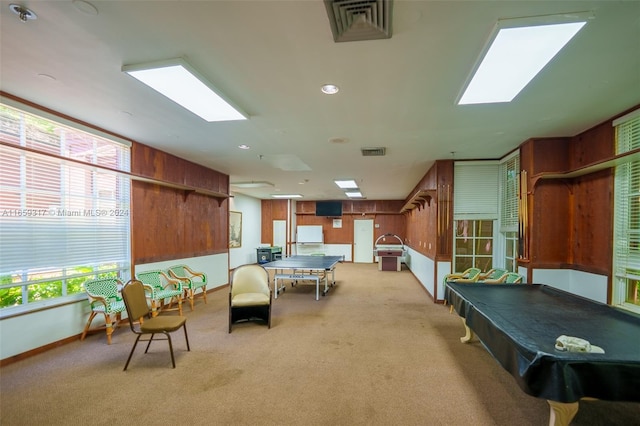 recreation room featuring a skylight, wooden walls, and light carpet